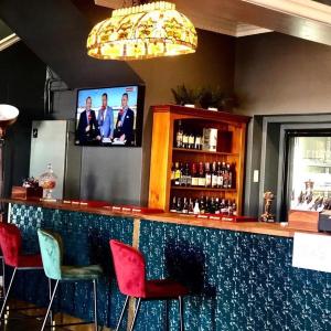 a bar with red chairs and a flat screen tv at Windsor Hotel Miles in Miles