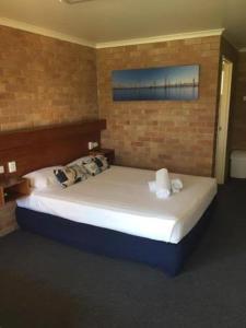 a bedroom with a large bed in a brick wall at Windsor Hotel Miles in Miles