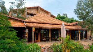 a wooden house with a roof with a patio at Vintage Cottage in Rwamagana