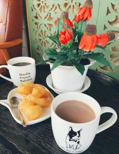 una mesa con dos tazas de té y un jarrón con flores en My Bunk Hostel en Ko Samed