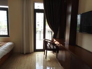 Cette chambre comprend un lit et un bureau avec une télévision. dans l'établissement An Phú Nguyễn Hoàng Hotel, à Hanoï