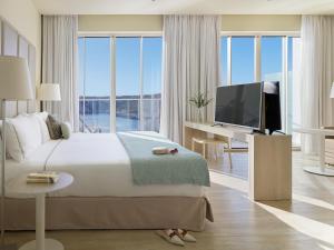 a bedroom with a large bed and a television at Meliá Cala Galdana in Cala Galdana