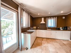 a kitchen with white cabinets and a large window at Le Petit Rossignol in Apt