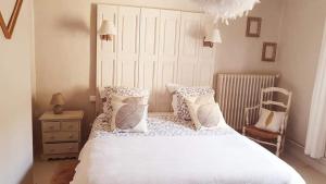 a bedroom with a white bed with pillows and a chair at Le 4 Feuilles en.Camargue in Bernis