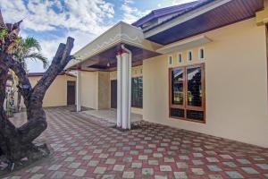 a house with a courtyard with a palm tree at Super OYO Capital O 90643 Suri Guest House Syariah in Padang