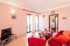 un soggiorno con sedie rosse e TV di Guesthouse Somnium a Cavtat