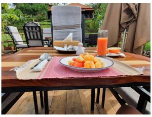 una mesa con un plato de fruta y un vaso de zumo de naranja en Vintage Cottage en Rwamagana