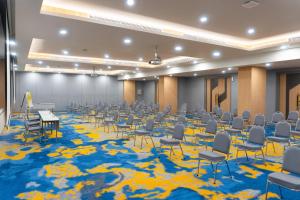 Habitación grande con sillas y mesas sobre una alfombra azul. en Yello Hotel Jambi en Jambi