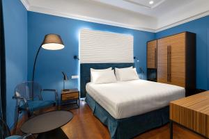 a blue bedroom with a bed and a table and a chair at Hotel Poerio 25 Boutique Stay in Naples