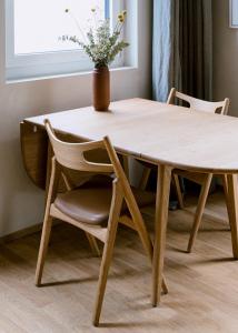 ein Holztisch und ein Stuhl mit einer Vase oben in der Unterkunft Feldberg Atelier - Courtyard Maisonette in Basel