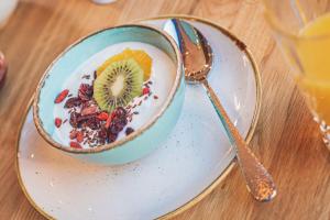 a bowl of cereal and fruit on a plate with a spoon at Hotel & Restaurant Posthalterei in Zusmarshausen