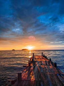 een houten pier in de oceaan met een zonsondergang bij Kaibae Hut Resort in Ko Chang