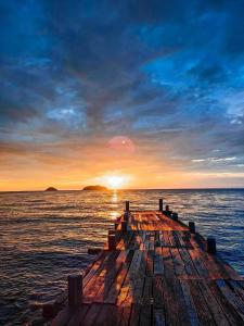 a wooden pier in the ocean with a sunset at Kaibae Hut Resort in Ko Chang