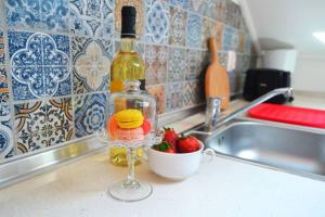 - une bouteille de vin et un bol de fraises sur un comptoir de cuisine dans l'établissement Lazy Lizard Studio, à Seixal