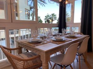 a dining room with a table with chairs and windows at Malagueta Beach Front Mediterranean Apartment in Málaga