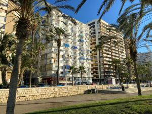 a tall building with palm trees in front of it at Malagueta Beach Front Mediterranean Apartment in Málaga