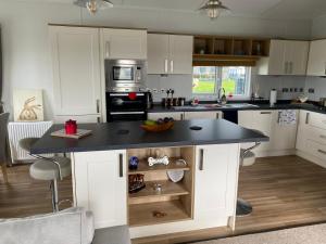a kitchen with white cabinets and a black counter top at Morwenna Lodge in Bude