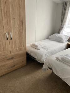a bedroom with two beds and a cupboard at Morwenna Lodge in Bude