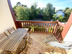 d'une terrasse avec une table et des chaises en bois sur un balcon. dans l'établissement L'OREE DE DEAUVILLE, CHARMANT DUPLEX PROCHE PLAGE, à Tourgéville