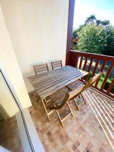 d'une table en bois et de deux chaises sur un balcon. dans l'établissement L'OREE DE DEAUVILLE, CHARMANT DUPLEX PROCHE PLAGE, à Tourgéville