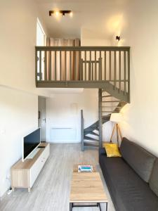 a living room with a couch and a staircase at L'OREE DE DEAUVILLE, CHARMANT DUPLEX PROCHE PLAGE in Tourgeville