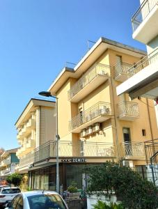 a building with balconies and cars parked in front of it at Hotel Zenith in Rimini