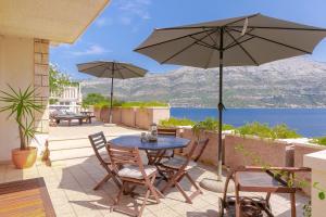 eine Terrasse mit einem Tisch, Stühlen und einem Sonnenschirm in der Unterkunft Villa Leda in Korčula