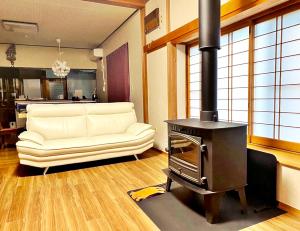 a living room with a white couch and a wood stove at 1日1組限定-伊那谷別邸-share old folk house- in Ina