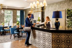 a man and woman standing at a bar in a hotel room at Mercure Bournemouth in Bournemouth