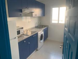 kuchnia z niebieskimi szafkami i pralką w obiekcie Apartamentos Tao Noah w mieście Puerto del Rosario