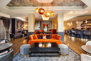 a living room with an orange couch and a bar at Queens Hotel & Spa Bournemouth in Bournemouth