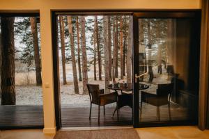 a glass door leading to a patio with a table and chairs at GaujaUpe in Gauja