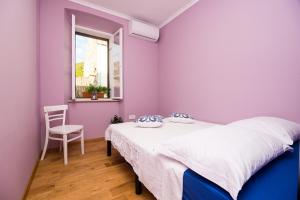 1 dormitorio con paredes moradas, 1 cama y 1 silla en Villa Nives en Žuljana
