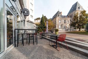stół i krzesła siedzące poza budynkiem w obiekcie Appart’City Confort Lyon Cité Internationale w mieście Caluire-et-Cuire