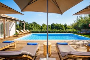 a swimming pool with two chairs and an umbrella at Abacatus Farmhouse in Tavira