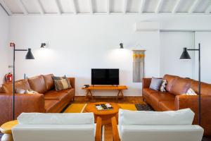 sala de estar con sofás de cuero marrón y TV en Abacatus Farmhouse, en Tavira