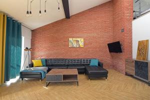 a living room with a couch and a brick wall at Sun&Sport Apartament PANORAMA dwupoziomowy i przestronny in Szczyrk