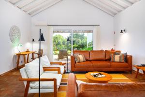 ein Wohnzimmer mit Ledersofas und einem Tisch in der Unterkunft Abacatus Farmhouse in Tavira