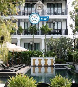 a hotel with a swimming pool in front of a building at Aksara Heritage -SHA Extra Plus in Chiang Mai