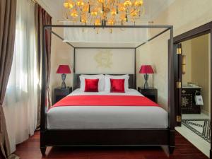 ein Schlafzimmer mit einem großen Bett mit roten Kissen in der Unterkunft Sofitel Legend Old Cataract in Assuan