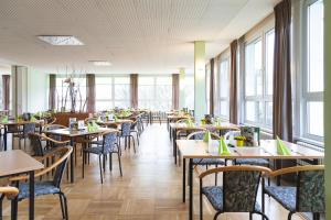 un comedor con mesas, sillas y ventanas en Werrapark Familienresort Hotel Heubacher Höhe, en Masserberg