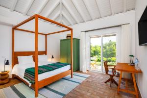a bedroom with a canopy bed and a desk at Abacatus Farmhouse in Tavira +53 photos