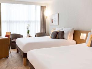 um quarto de hotel com duas camas e uma cadeira em Novotel Genève Centre em Genebra