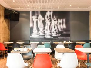 uma sala de jantar com mesas e cadeiras e uma fotografia de xadrez em ibis Bordeaux Centre Bastide em Bordéus