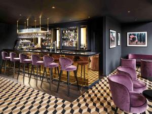 bar z fioletowymi stołkami w pokoju w obiekcie Mercure Edinburgh City - Princes Street Hotel w Edynburgu