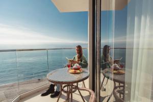 two women sitting at a table on a balcony with the ocean at Luchezarniy Resort in Loo