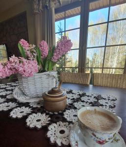 een tafel met een kopje koffie en een mand met bloemen bij Zacisze Jurajskie in Olsztyn
