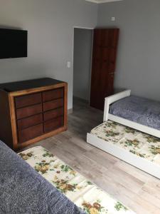 1 dormitorio con 2 camas, vestidor y TV en La Casa de Monte en Monte Hermoso