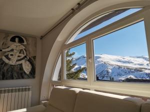 a room with a couch and a window with a mountain view at Chalet Adosado Urbanización COPOS PREMIUM Zona Media in Sierra Nevada
