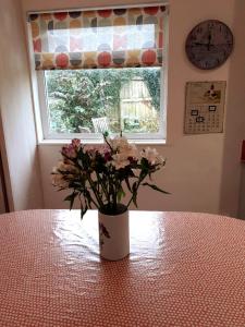 eine Vase von Blumen, die auf einem Tisch vor einem Fenster sitzt in der Unterkunft Entire house near beaches, footpaths, dog friendly in Barnstaple